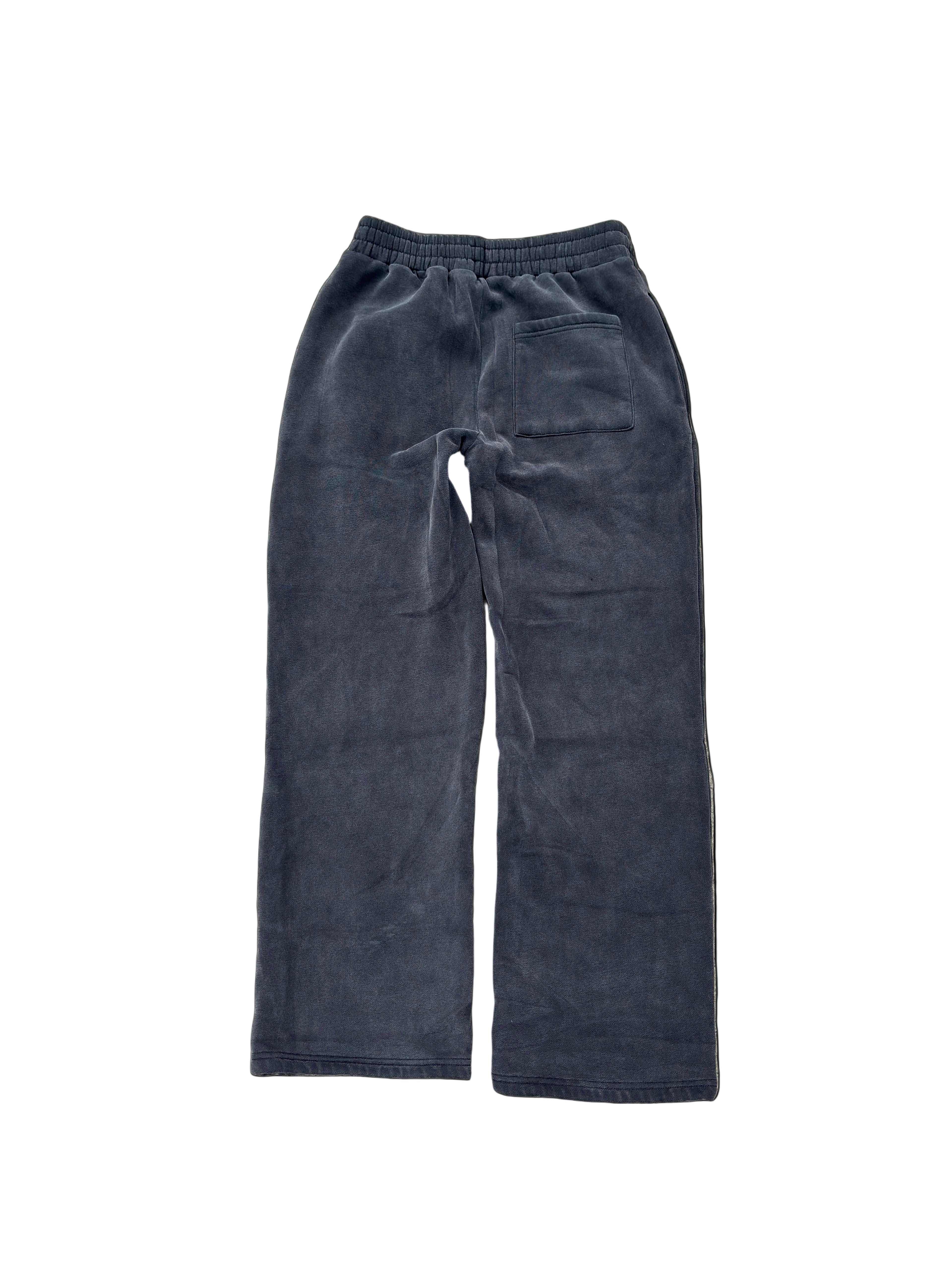 Pair of dark blue corduroy pants on a textured beige surface